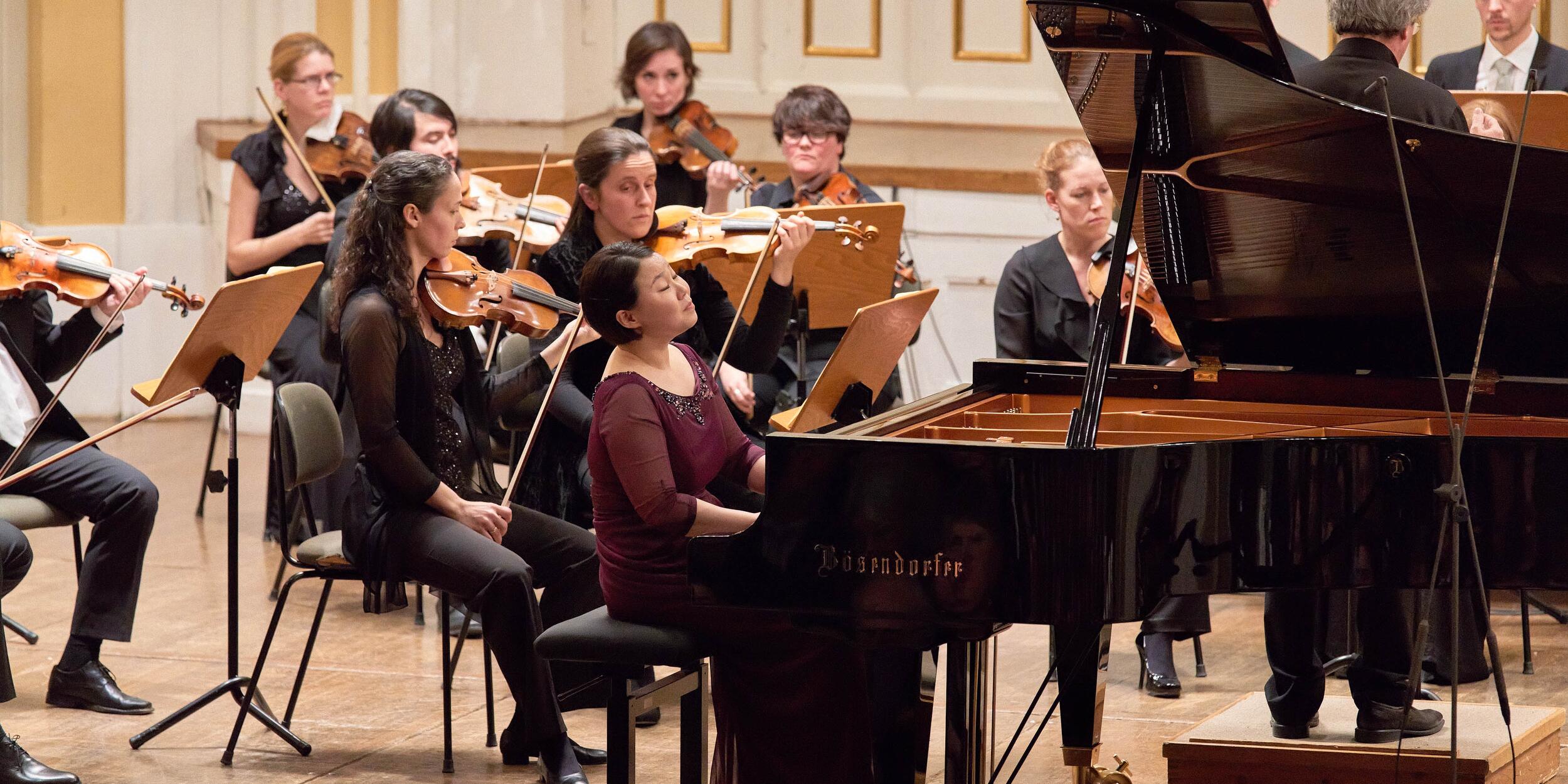 Pianistin an einem Flügel, dahinter Streicher | © Christian Schneider