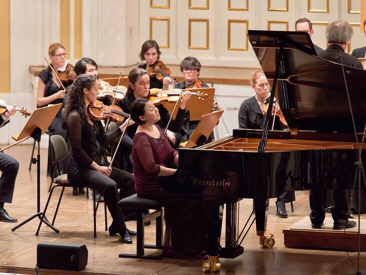 Pianistin an einem Flügel, dahinter Streicher | © Christian Schneider