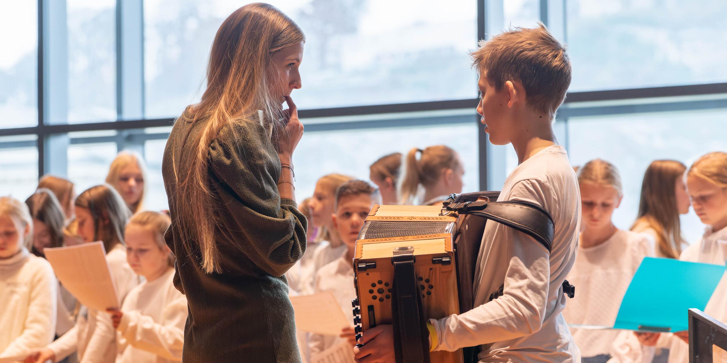 Kinderchor mit Lehrerin und Jungen mit Akkordeon | © Christian Schneider